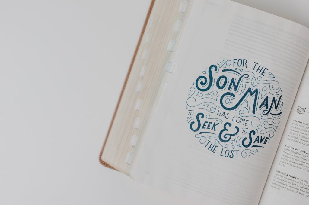pexels-photo-8383410 High-angle view of an open Bible with an inspirational scripture quote on a white surface.